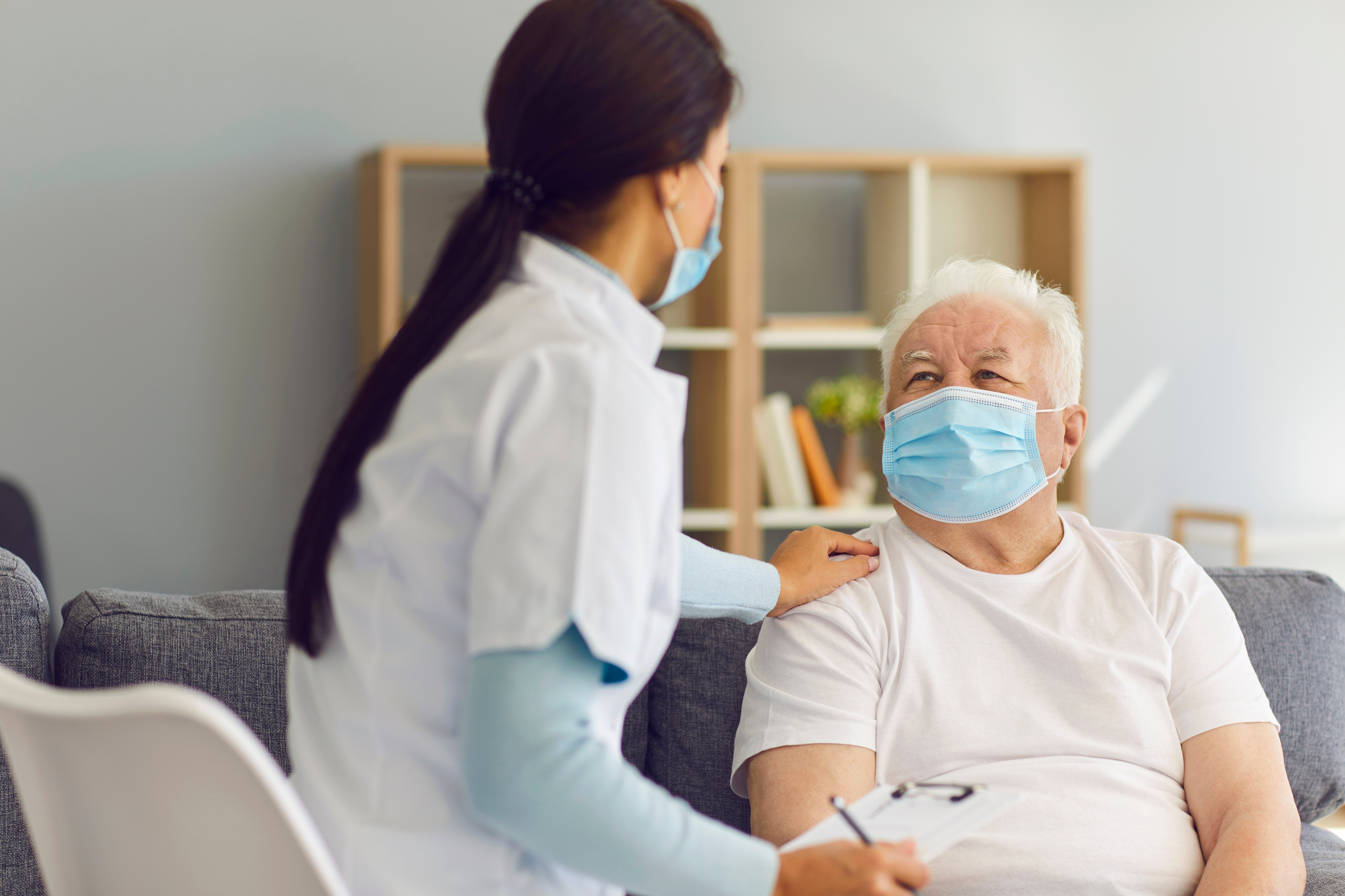 Caring Supportive Doctor Visiting Senior Male Patient at Home during Coronavirus Pandemic